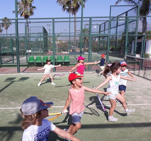 niños y niñas entrenado en la pista de padel